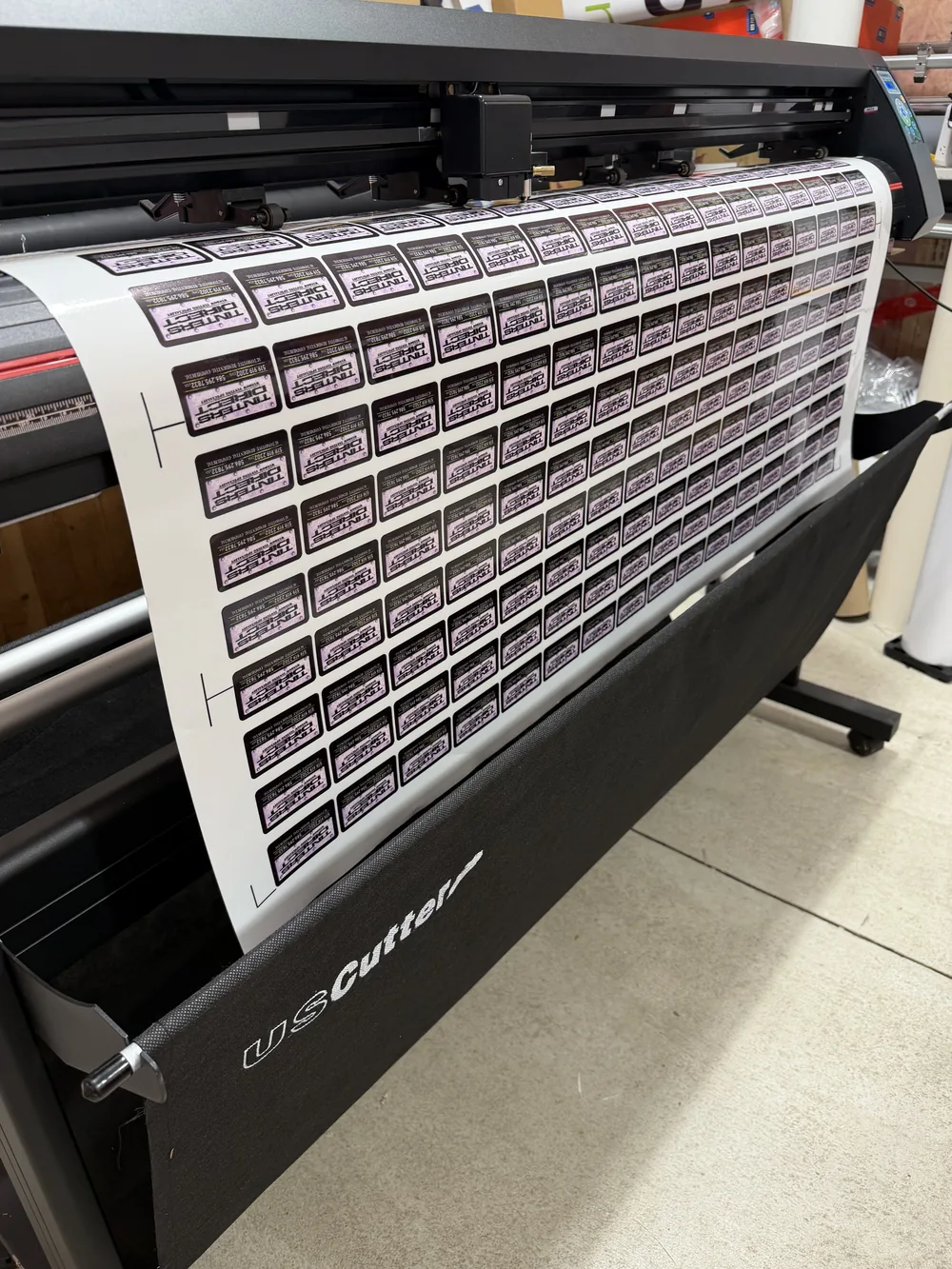 A sheet of printed custom stickers running through a vinyl cutter