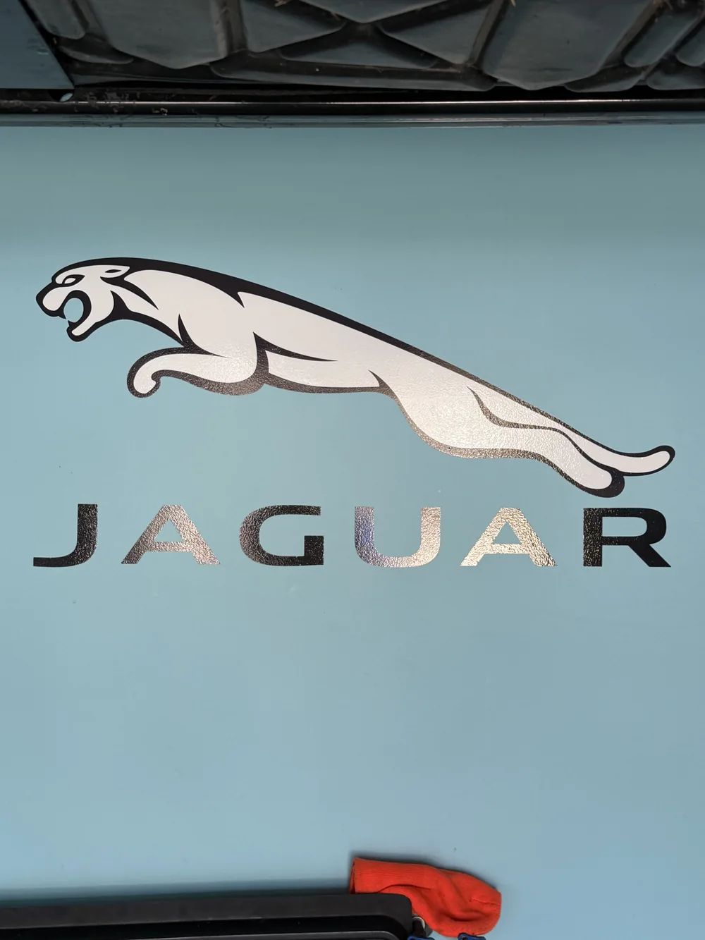 Metallic Jaguar lettering and leaping cat graphic on a blue surface